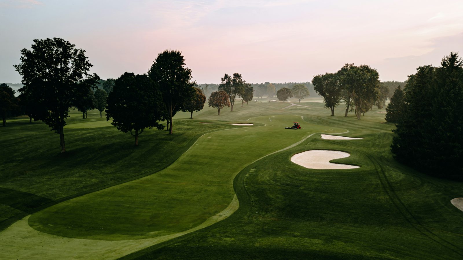Oak Crest opening hole, a manicured green framed by bunkers at dawn